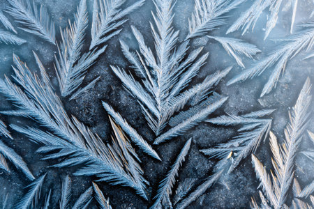 Close up of delicate frost patterns creating a cold, natural winter background textureの素材