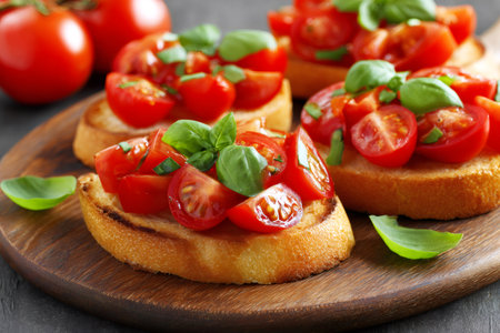 Bruschetta preparing with chopped tomatoes and fresh basil on toasted bread slicesの素材