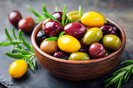 Mixed olives of various colors with fresh rosemary sprigs served in a rustic bowlの素材