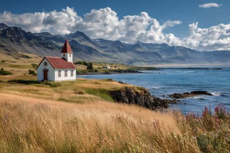 White church with red roof set against ocean, mountains, and summer cloudsの素材
