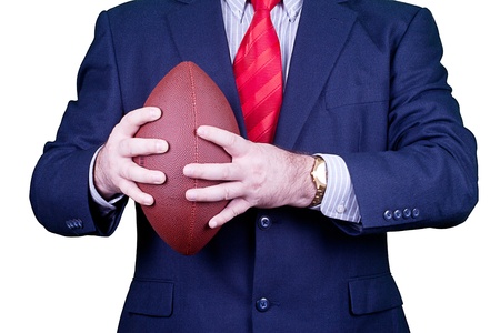 Businessman in suit and red tie holding a football.の写真素材
