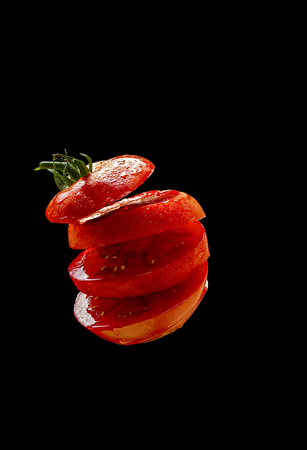 5 Flying tomato slices on a black backgroundの写真素材