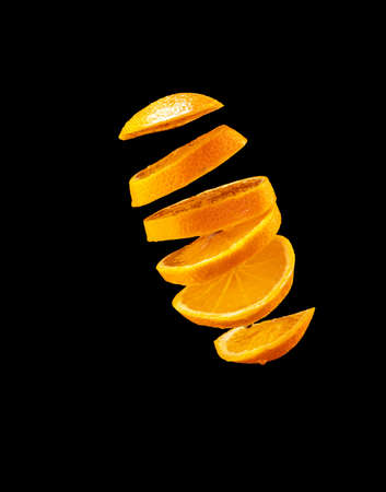 Falling orange and orange slices. Isolated on a black.の写真素材