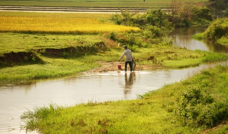 Farner working on farmland, he take water into spayer from ditch in Daklak, Viet Nam, September 5, 2012     のeditorial素材