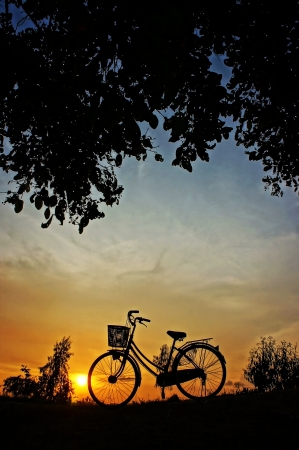 Beautiful landscape of nature with impression of the sun  and silhouette of bicycle  in sunset at countrysideの写真素材