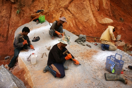  Worker swith splitter and hammer on hand try to carve out  large rock into small size for...