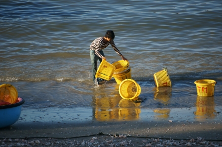 PHAN THIET, VIET NAM- FEB 3  Fisherman wash plastic basket by water at beach in Phan Thiet, Viet Nam on Feb 3, 2013のeditorial素材