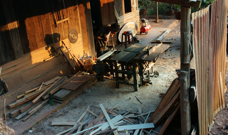 DALAT, VIETNAM- JAN 24: Carpenter saw wood by power saw at home, he working with concentration, his shadow reflect on the wall of wooden house, Viet Nam, Jan 24, 2014                           のeditorial素材