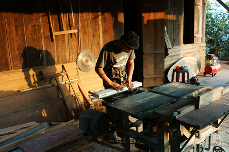 DALAT, VIETNAM- JAN 24: Carpenter saw wood by power saw at home, he working with concentration, his shadow reflect on the wall of wooden house, Viet Nam, Jan 24, 2014                           のeditorial素材
