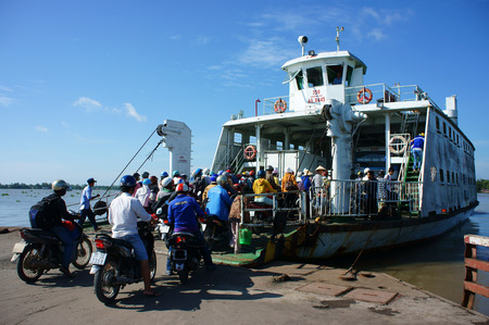 MEKONG DELTA, VIETNAM- JULY 7  Crowd of people wear heltmet sitting on motorbike to cross the river by ferry boat, this is  passenger transport vehicle on water at My Loi ferry, Viet Nam, July 7, 2014のeditorial素材