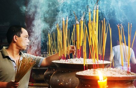 HO CHI MINH CITY, VIETNAM- AUG 10   People burn incense at ancient pagoda, incense stick in censer, smoke spriral, this traditional culture of buddhism religion, man in solemn, Vietnam, Aug 10, 2014のeditorial素材