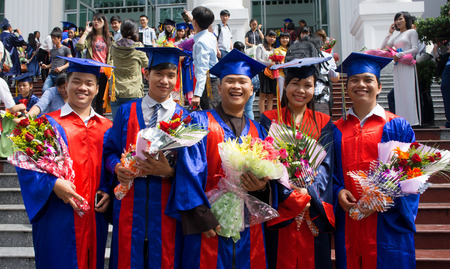 HO CHI MINH CITY, VIETNAM- AUG 8   Group of young student in gown uniform standing, hold bouquet, smile on graduate ceremony at university, young girl happy with bright future, Viet Nam,  Aug 5, 2014のeditorial素材