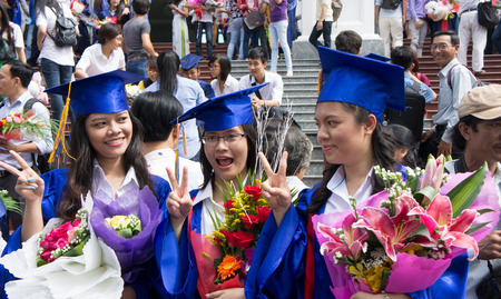 HO CHI MINH CITY, VIETNAM- AUG 8   Group of young student in gown uniform standing, hold bouquet, smile on graduate ceremony at university, young girl happy with bright future, Viet Nam,  Aug 5, 2014のeditorial素材