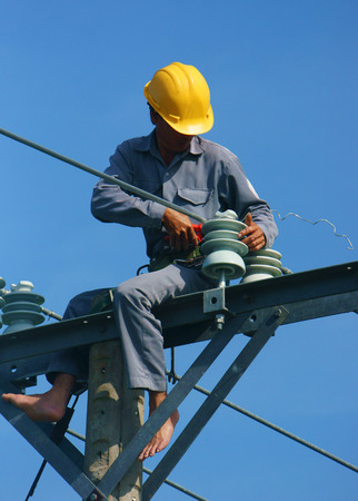 DONG THAP, VIET NAM- SEPT 23:  Asian electrician climb high in pole to work, lineman with cable network, man repair electric post danger and unsafe, is industry service, Vietnam, Sept 23, 2014のeditorial素材