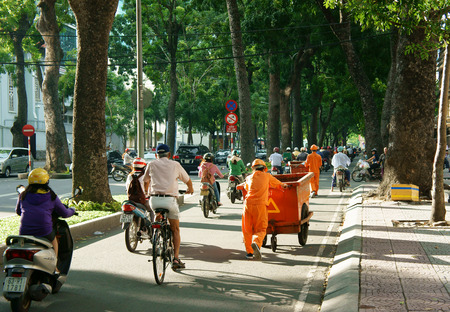 HO CHI MINH CITY, VIET NAM- SEPT 7: Asia city scene at evening, sanitation worker work on road, vehicle as bicycle, motorbike in traffic, Ton Duc Thang street with row of tree, Vietnam, Sept 7, 2014のeditorial素材