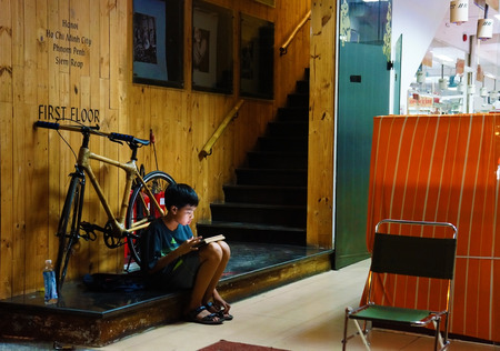 HO CHI MINH CITY, VIET NAM- OCT 12: Unidentified Asian children sitting at staircase of house with tablet, Vietnamese kid looking with high concentration, modern technology, Vietnam, Oct 12, 2014のeditorial素材