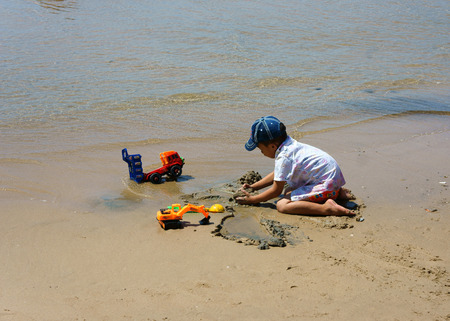 BINH THUAN, VIET NAM- OCT 25: Unidentified Asian kid playing on Vietnamese beach, little boy play alone with toy at seaside, Vietnam, Oct 21, 2013のeditorial素材