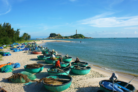 Beautiful landscape of Vietnam beach, group of boat on sand, people travel at seashore, Ke Ga cape faraway, blue sky, green tree make nice scene for Viet Nam travelのeditorial素材
