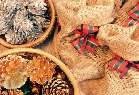 Xmas gift and pine cone in basket, decoration for christmas season, present bag from burlap, with amazing knotの写真素材