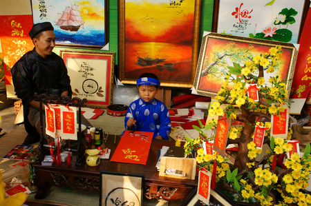 HO CHI MINH CITY, VIET NAM- FEB 7: Atmosphere of springtime with colorful scene, unidentified Vietnamese kid in ao dai, write chinese writing or calligraphy at spring fair on Tet, Vietnam, Feb 7, 2015のeditorial素材