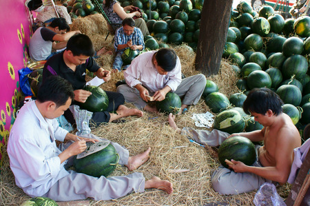 HO CHI MINH CITY, VIET NAM- FEB 12: Group of Asian man working on pavement of farmer market, Vietnamese male engraving onto watermelon to decoration on Tet, happy face with art, Vietnam, Feb 12, 2015のeditorial素材