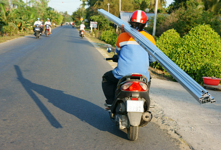 BEN TRE, VIET NAM- MAR 24: Transportation goods on street in danger by motorbike, Asian man ride one hand, carry heavy, overloaded traffic, this is unsafe, can make accident, Vietnam, Mar 24, 2015のeditorial素材