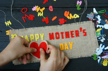 Happy mothers day with i love mom message,  idea from colorful letter on wooden background, woman hand cutting character to make gift for mother on happy day, show feeling with mother, love familyの写真素材