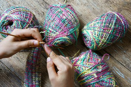 Women hand knitting wool glove to make christmas present, a special gift for cold winter, colorful wool ball, two point needle on wooden backgroundの写真素材