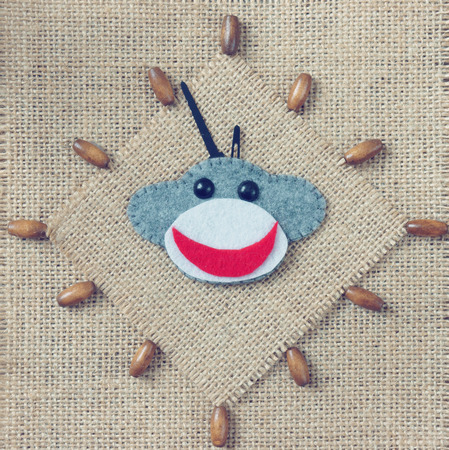 Art idea with funny monkey for happy new year 2016, new year eve time, handmade monkey face, clockwise on hand made clock, heart, flower decor on burlap background, vintage conceptの写真素材