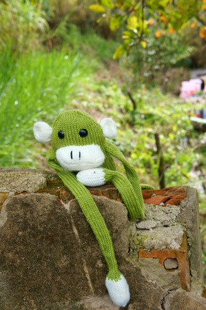 Abstract knitted monkey, symbol of year 2016, handmade toy from yarn, she lie down or sit lonely...