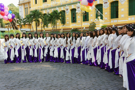HO CHI MINH CITY, VIET NAM- NOV 24: Crowd of Vietnamese student in traditional dress, ao dai, shooting for yearbook at Saigon central post office, Vietnam, Nov 24, 2015のeditorial素材