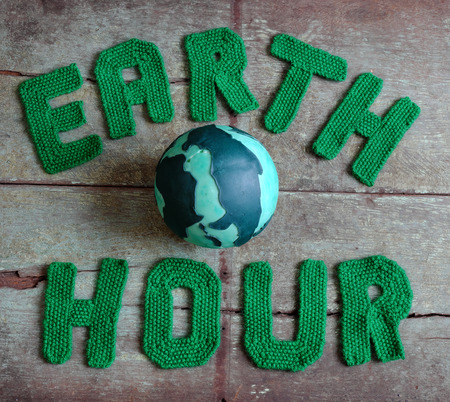 Earth hour letter in green yarn on wood background, a symbol for save the planet from climate change, handmade  message for worldwideの写真素材