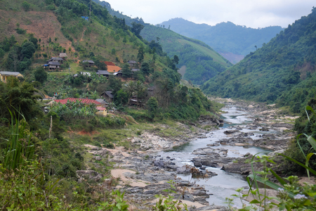 Scene on Ho Chi Minh trail on clouds day, house on hill, danger terrain with mountain pass, people cross stream, life on highland Vietnam among green forestの写真素材