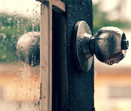 Rain drops on door handle and glass window in rainy day, drop of water falling make lonely feeling of cold dayの写真素材
