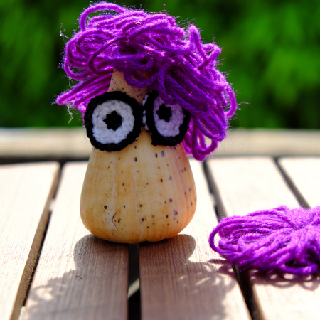 Funny creative from hobby, owl make from conch shell with knitted eyes, violet wool hair on green background, amazing diy ornament with enjoyment lifeの写真素材