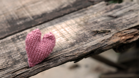 Lonely heart on wooden background, symbol of love with pink knitted heart in vintage colorの写真素材