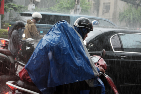 HO CHI MINH CITY, VIET NAM- AUG 28, 2016: Group of Vietnamese people wear helmet and raincoat ride motorbike in heavy rain, water on street, this time is rainy season at Saigon, Vietnamのeditorial素材