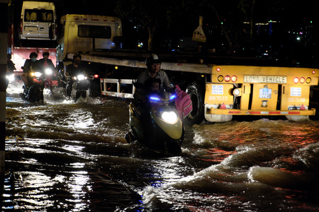 HO CHI MINH CITY, VIET NAM- OCT 18, 2016: Awful flooded street at Asian city, crowd of people ride...