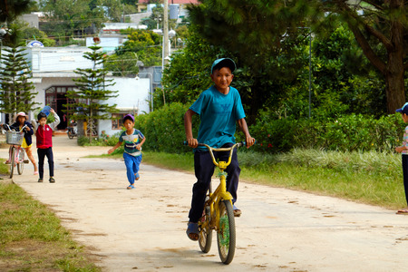 LAM DONG, VIET NAM-  DEC 28, 2016: Group of unidentified Vietnamese children ride bicycle on country road at noon, naughty boy run to tease his friend, Lamdong, Vietnamのeditorial素材