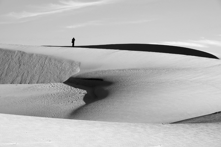 Life is the trip, lonely man enjoy calm scene on Vietnamese sand hill, sandhill with amazing shape in black and white tone in summertime, adventure travel in the choice of freedom young peopleの写真素材