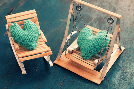 Two hearts be together, illustration for couple in love, take care and loving, green heart on handmade mini furniture as chair, swing, bed on wood backgroundの写真素材