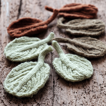 Amazing craft products from yarn, group knitted winter leaf on wooden background, beauty alder leaf with vintage toneの写真素材