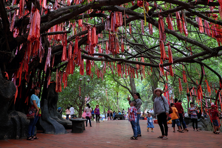 HO CHI MINH CITY, VIET NAM- JUNE 1, 2017: People hang red ribbons on love tree at Suoi Tien tourist area, place for cultural travel, Vietnamのeditorial素材