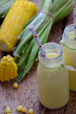 Healthy drinking for breakfast from sweetcorn, corn milk jar in yellow, rich vitamin, tasty, nutrition from maize, fresh milk bottle on wooden backgroundの写真素材