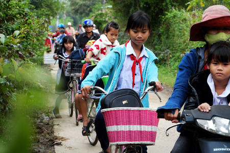BINH DINH, VIET NAM- NOV 3, 2017:Group of Vietnamese children coming home from school by bicycle, crowd Asian little girl ride cycle on country road, Vietnamのeditorial素材