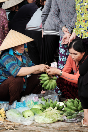 BINH DINH, VIET NAM- NOV 2, 2017: Group of Vietnamese woman purchase at outdoor farmer market at Vietnam countryside, traditional market at morning, food on ground of roadsideのeditorial素材
