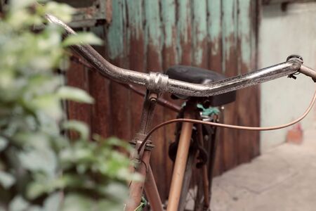 Amazing close up old bicycle front of antique house, wheel of bike rust, damaged with blurred background in vintage tone at China town, Vietnamの写真素材