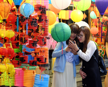 HO CHI MINH CITY, VIET NAM- SEPT 24, 2018: Group of Vietnamese beautiful young girls visit, have fun time, take a photo with friends at night lantern street, red vibrant at outdoor marketのeditorial素材