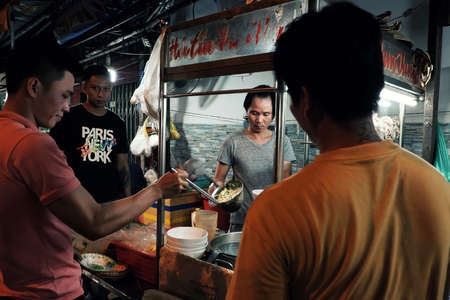HO CHI MINH CITY, VIET NAM- JULY 5, 2019: Vietnamese man cook noodle soup on food cart at night street food, hot noodles bowl with meat, shrimp so delicious to eat, Vietnamのeditorial素材