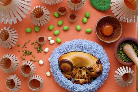Top view of moon cake with mother pig and piglets shape, baking materials, paper lanterns, traditional baked pastry for mid autumn season on orange backgroundの写真素材